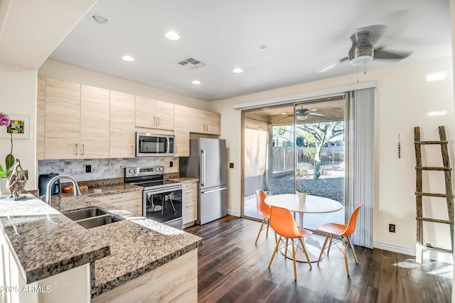 kitchen featuring appliances with stainless steel finishes, sink, dark stone countertops, decorative backsplash, and kitchen peninsula