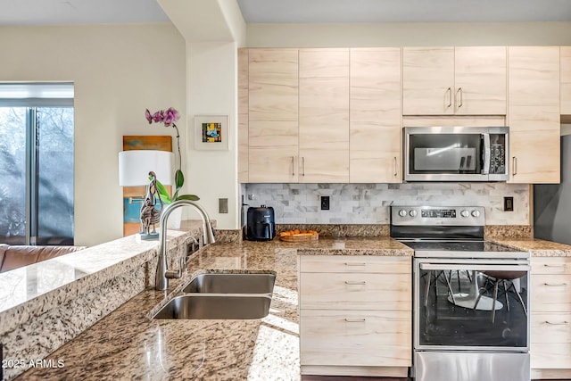 kitchen with sink, light stone countertops, and appliances with stainless steel finishes