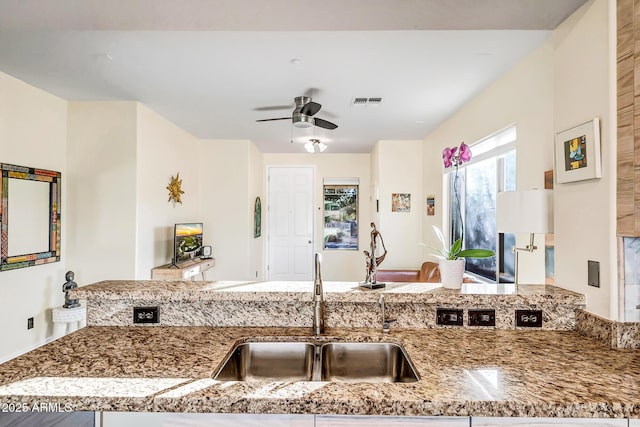 kitchen with sink, light stone countertops, kitchen peninsula, and ceiling fan