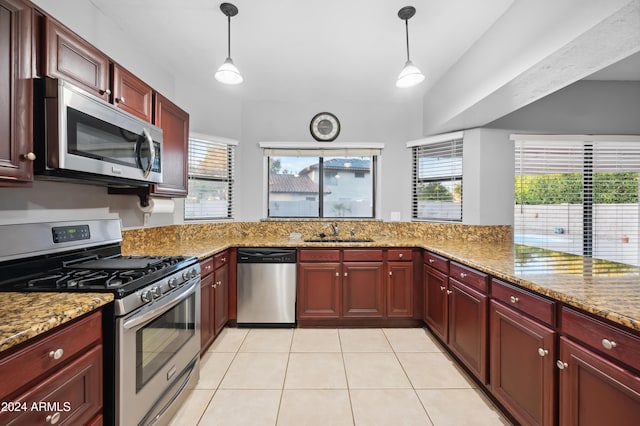 kitchen with light stone counters, sink, stainless steel appliances, and hanging light fixtures