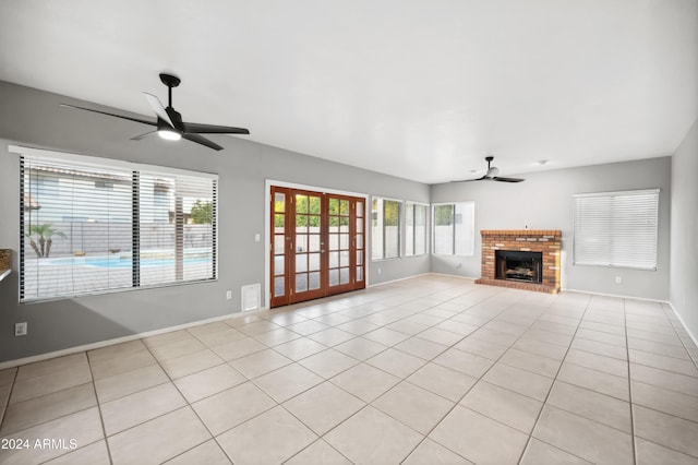 unfurnished living room featuring ceiling fan, light tile patterned flooring, a fireplace, and french doors