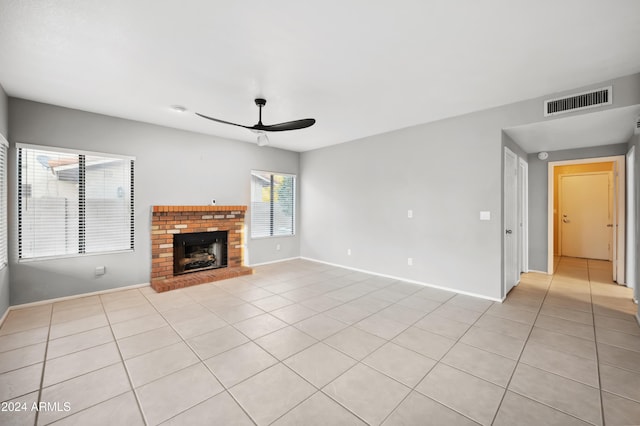 unfurnished living room with ceiling fan, a fireplace, and light tile patterned flooring