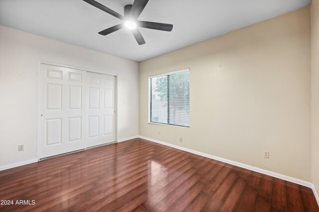 unfurnished bedroom featuring ceiling fan, dark hardwood / wood-style flooring, and a closet