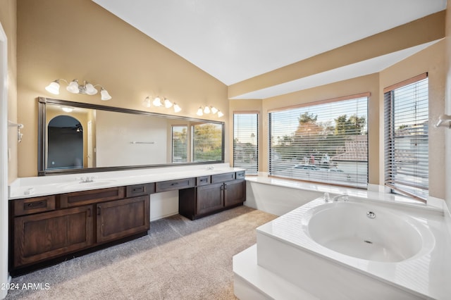 bathroom with a bathtub, vanity, and vaulted ceiling