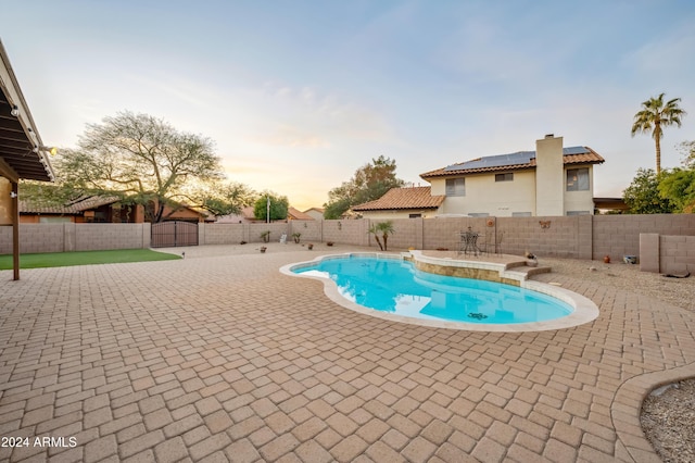 pool at dusk featuring a patio