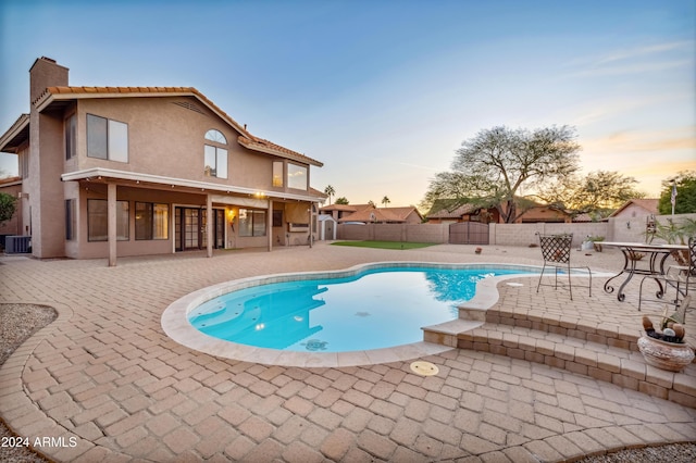 pool at dusk with a patio area