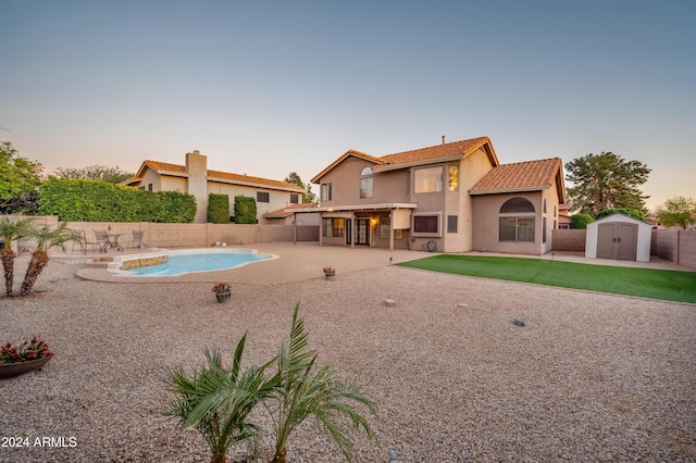 pool at dusk with a patio and a storage unit