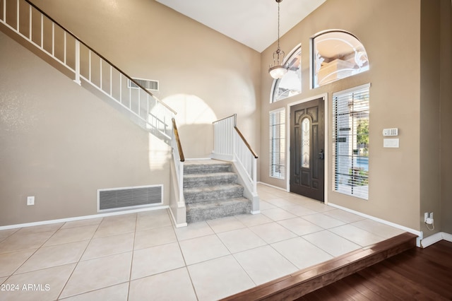 foyer with a chandelier, light tile patterned floors, and a towering ceiling