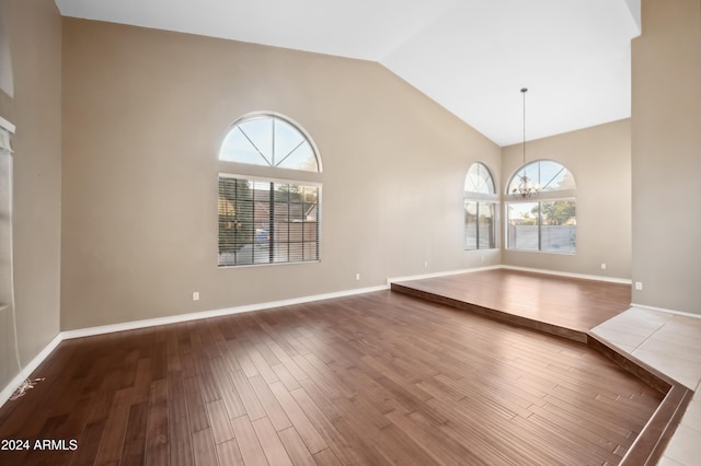 interior space with high vaulted ceiling, hardwood / wood-style flooring, and an inviting chandelier