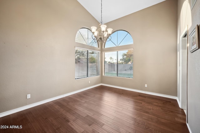 unfurnished dining area featuring high vaulted ceiling, a chandelier, and dark hardwood / wood-style floors