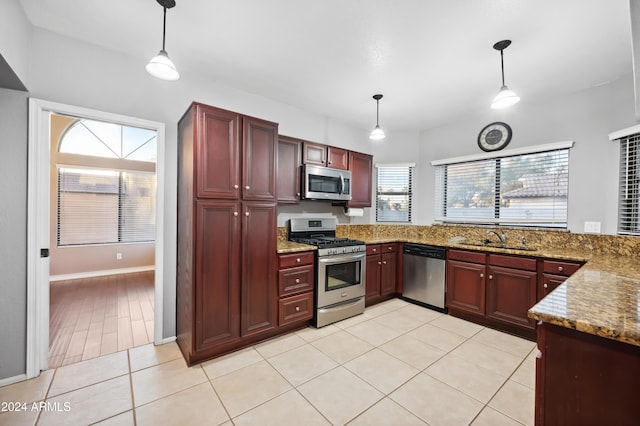 kitchen featuring light stone countertops, sink, stainless steel appliances, decorative light fixtures, and light tile patterned floors