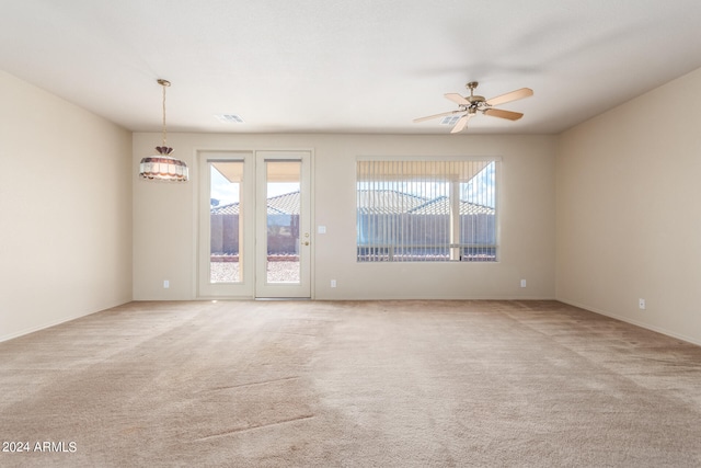 empty room with ceiling fan, light colored carpet, and plenty of natural light