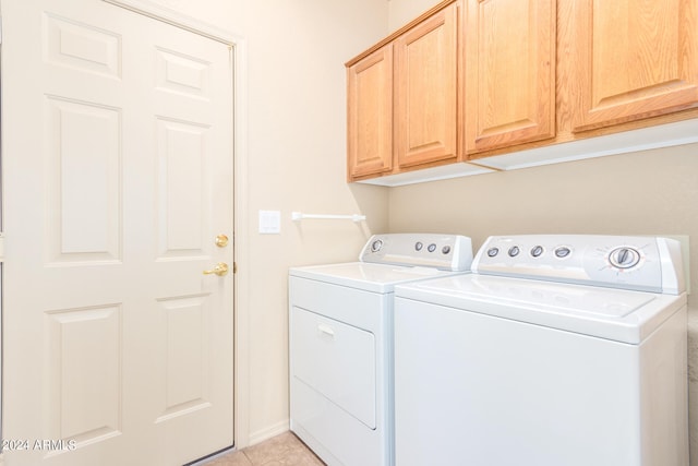 washroom with light tile patterned flooring, washing machine and clothes dryer, and cabinets