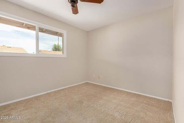 carpeted empty room featuring ceiling fan and baseboards