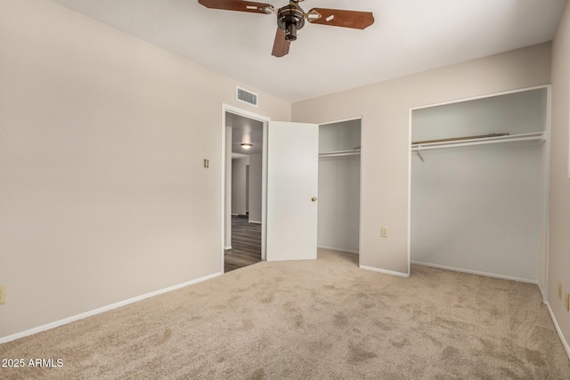 unfurnished bedroom with multiple closets, carpet floors, baseboards, and ceiling fan