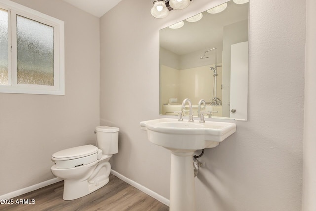 bathroom with toilet, baseboards, and wood finished floors