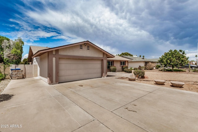 ranch-style home featuring an attached garage, concrete driveway, stucco siding, and fence