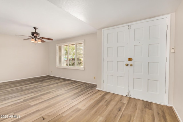 entryway with light wood-style floors, a ceiling fan, and baseboards