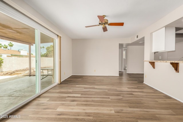 unfurnished living room with light wood-style floors, a ceiling fan, and baseboards