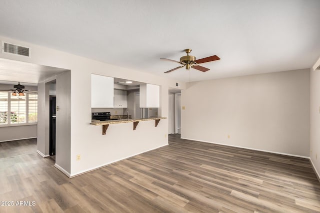 unfurnished living room featuring ceiling fan, wood finished floors, and baseboards