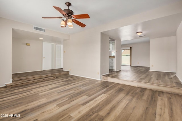 unfurnished living room featuring wood finished floors, ceiling fan, and baseboards