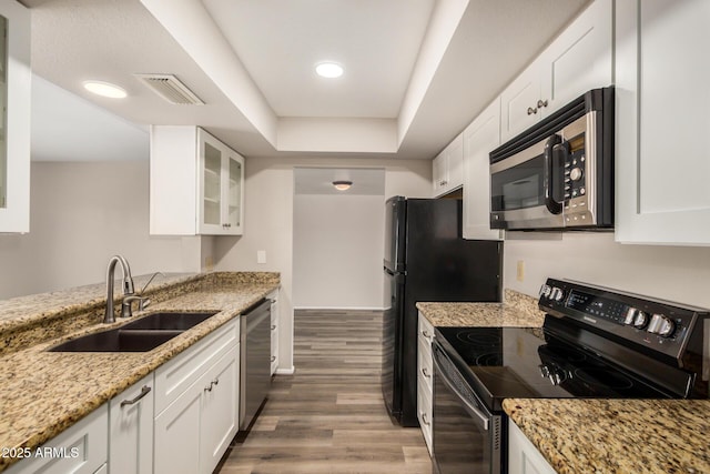 kitchen with black appliances, a sink, wood finished floors, white cabinetry, and recessed lighting