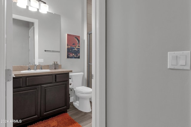 bathroom featuring hardwood / wood-style floors, vanity, an enclosed shower, and toilet