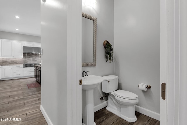 bathroom featuring decorative backsplash, hardwood / wood-style floors, toilet, and sink