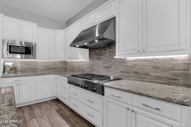 kitchen with white cabinets, light stone countertops, stainless steel appliances, and exhaust hood