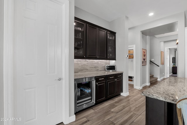 kitchen with light stone countertops, dark brown cabinetry, and wine cooler