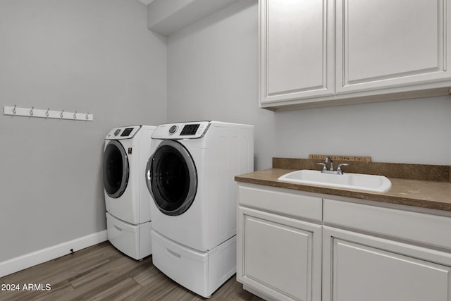 laundry room with washer and dryer, cabinets, wood-type flooring, and sink