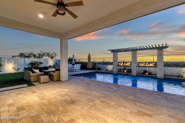 pool at dusk featuring pool water feature, ceiling fan, and a patio