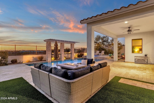 patio terrace at dusk with a fire pit, ceiling fan, and a water view