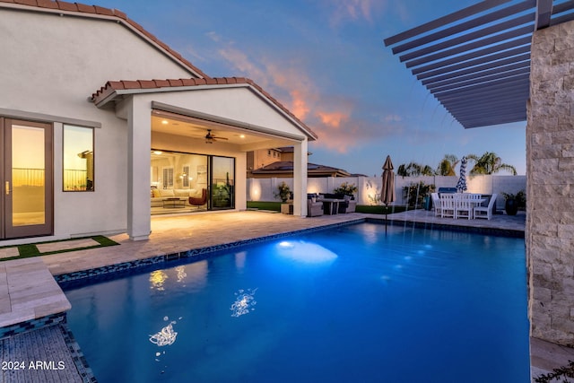 pool at dusk with a patio area and ceiling fan