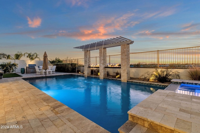 pool at dusk with a patio area and an in ground hot tub