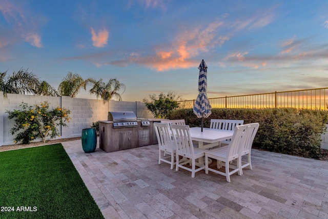 patio terrace at dusk with a grill and exterior kitchen