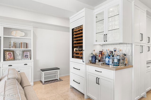 bar featuring backsplash, white cabinets, and light tile patterned floors