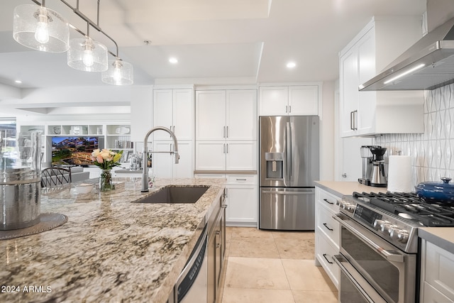 kitchen featuring white cabinets, appliances with stainless steel finishes, pendant lighting, and wall chimney exhaust hood