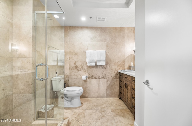 bathroom featuring vanity, a shower with door, toilet, and tile walls