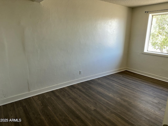 spare room with dark wood-style floors, baseboards, and a textured ceiling