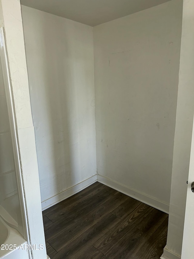 spare room featuring baseboards and wood finished floors