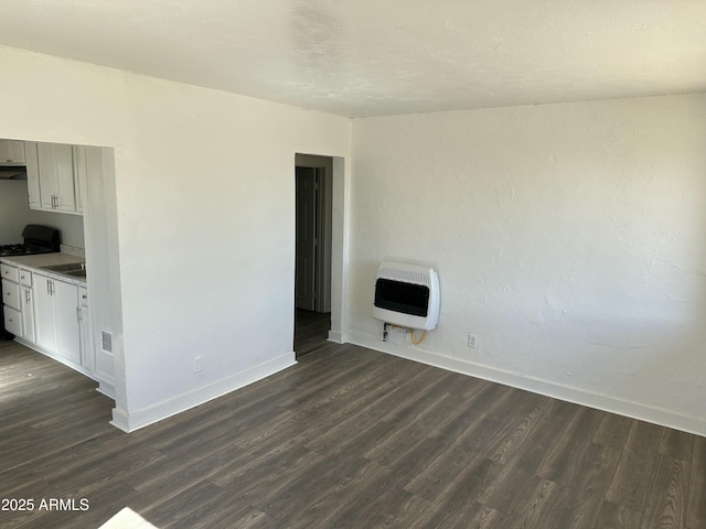 unfurnished living room with dark wood-type flooring, heating unit, visible vents, and baseboards