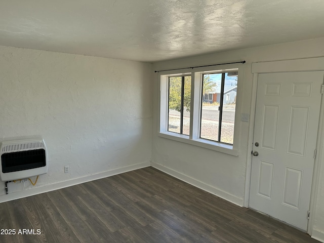 foyer entrance featuring baseboards, heating unit, dark wood-style flooring, and a textured wall