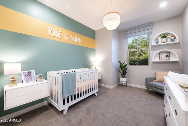 carpeted bedroom with an inviting chandelier and a nursery area