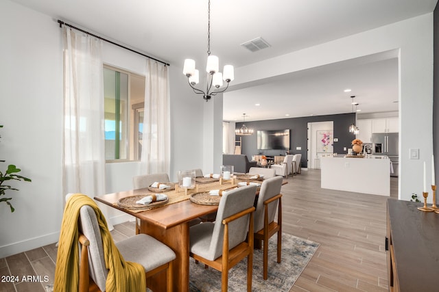 dining area with light hardwood / wood-style flooring and a chandelier