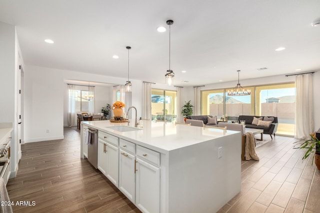 kitchen featuring white cabinetry, sink, dishwasher, hardwood / wood-style floors, and a center island with sink