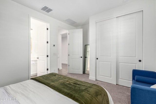 bedroom featuring ensuite bathroom, light colored carpet, and a closet