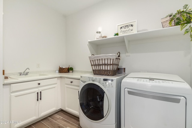 laundry room featuring washing machine and clothes dryer, dark hardwood / wood-style flooring, cabinets, and sink