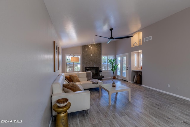 living room featuring wood-type flooring, a large fireplace, high vaulted ceiling, and ceiling fan