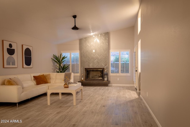 living room featuring hardwood / wood-style floors, a healthy amount of sunlight, lofted ceiling, and a large fireplace